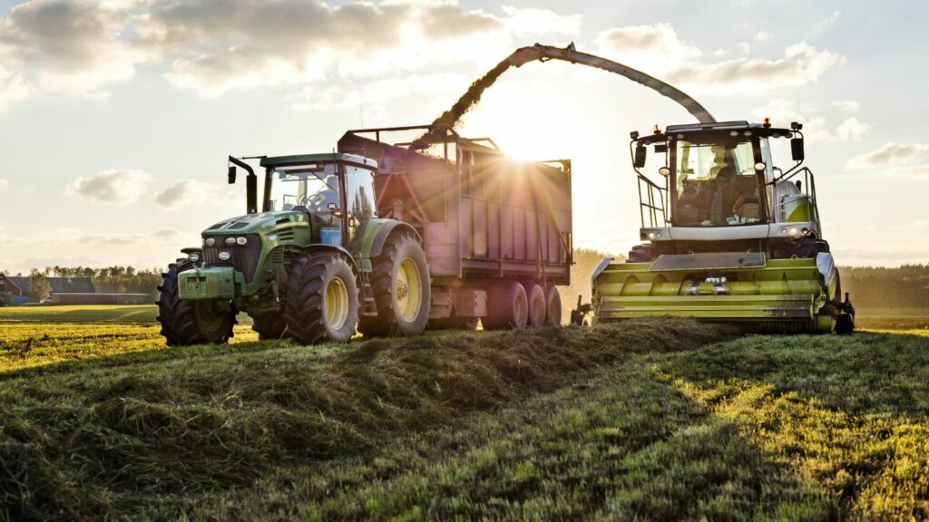 Tractors working in a field during sunset, highlighting agricultural operations and the importance of security for farm equipment and resources.