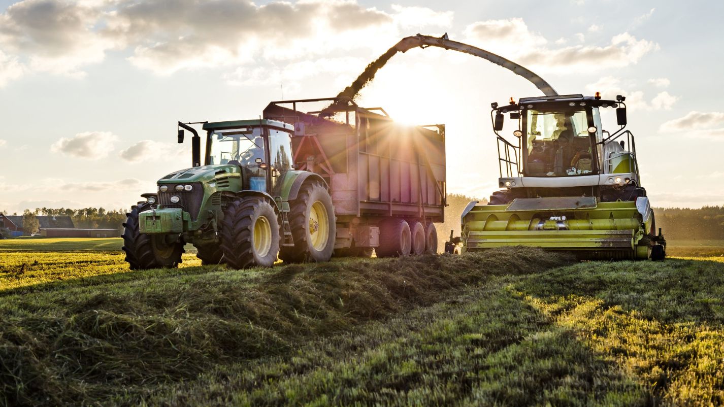 Tractors harvesting crops in a field at sunset, showcasing agricultural machinery for security solutions in farming.